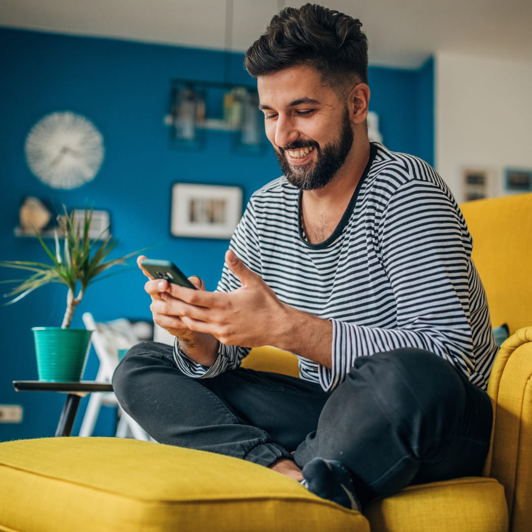 Empowered Women (1) guy seated with folded legs on chair holding phone