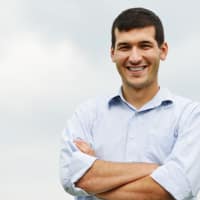 Untitled design (8) smiling man standing with folded arms